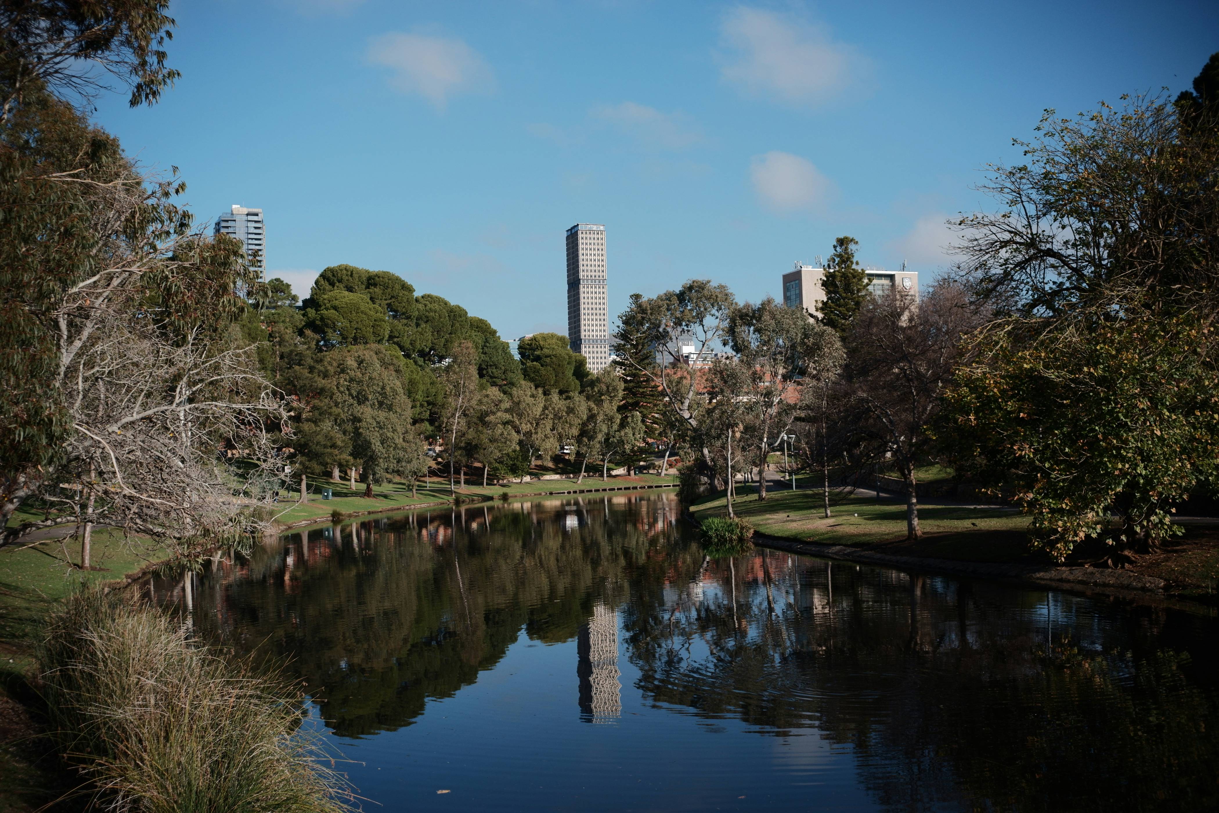 A river flows through a green park and city.