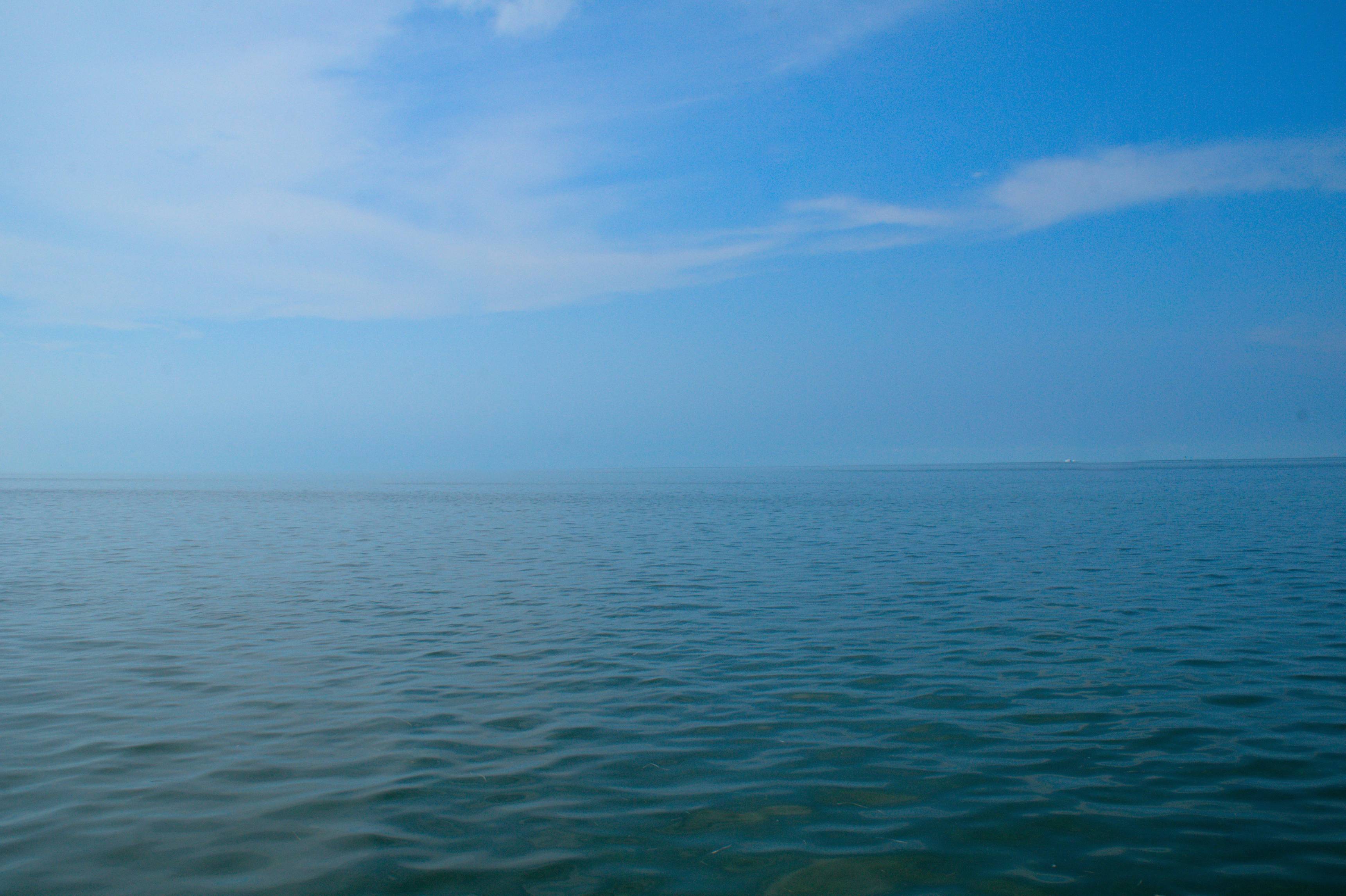 a body of water with a blue sky and clouds