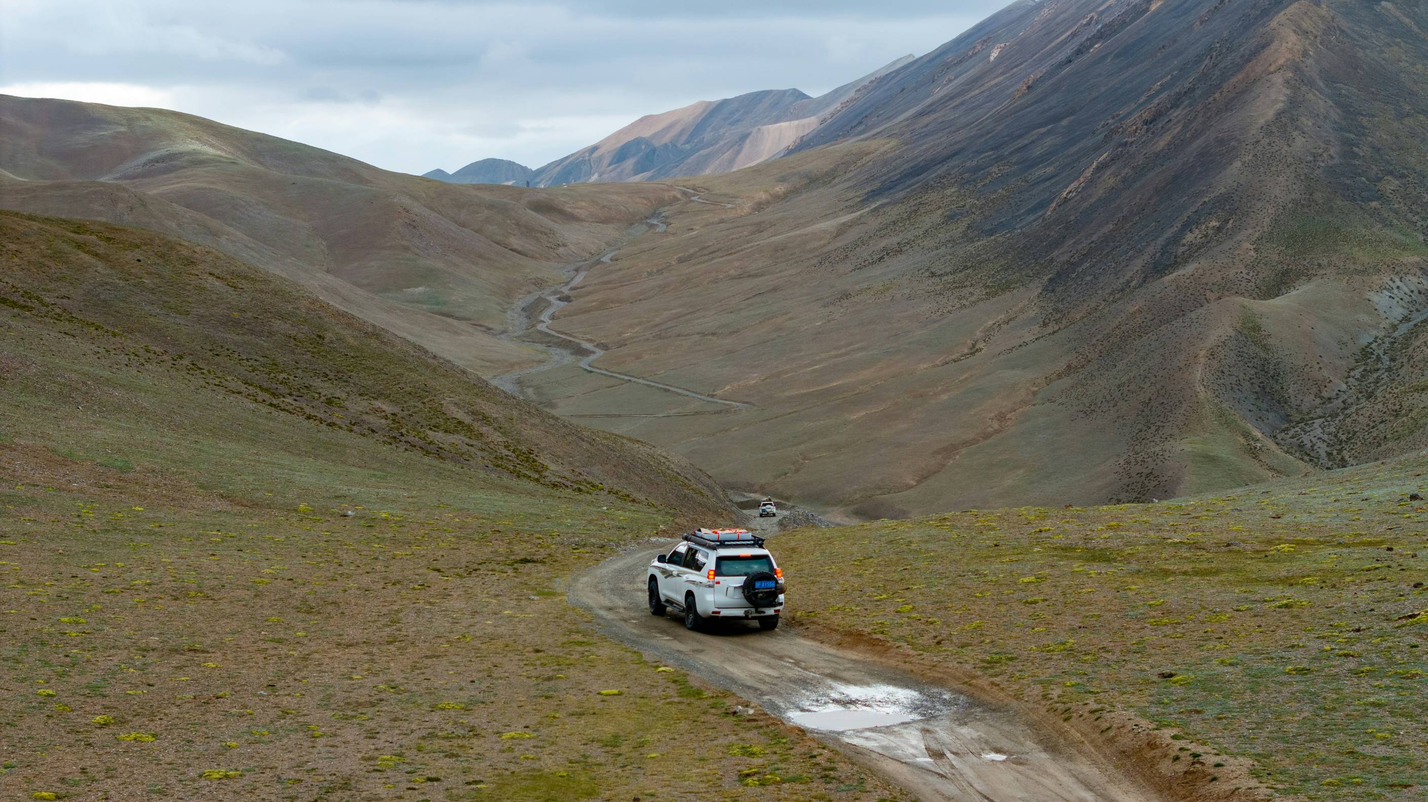 A car driving down a dirt road in the mountains